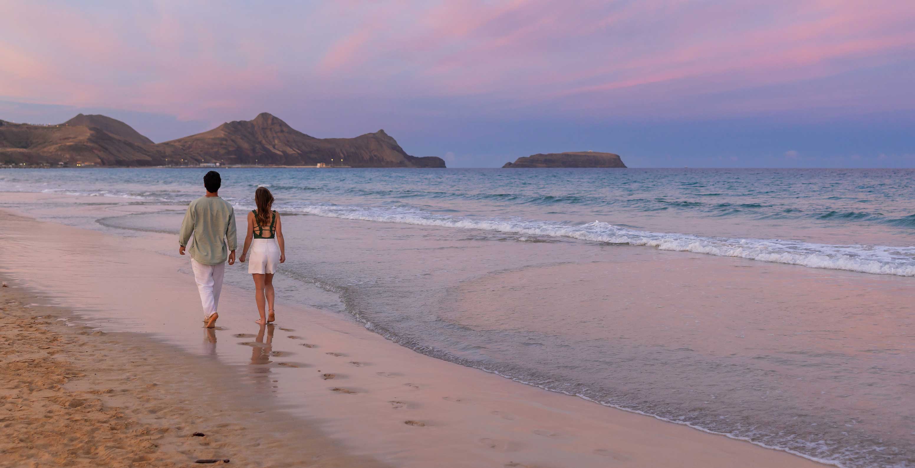 Um casal a passear à beira-mar na praia da ilha do Porto Santo, em frente ao Pestana Porto Santo All Inclusive 