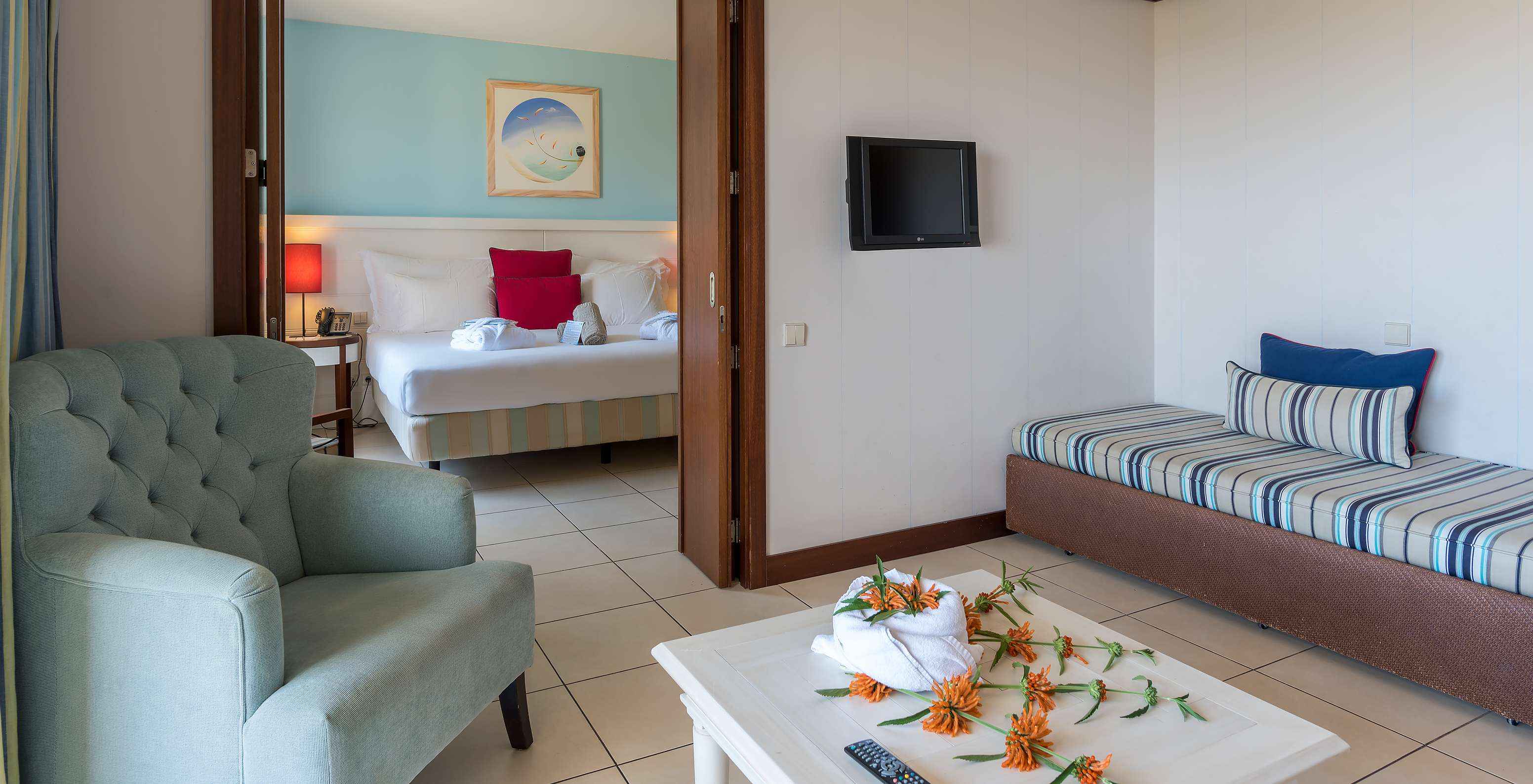 A Suite Apartamento T1 do Pestana Porto Santo All Inclusive tem um quarto com cama de casal e uma sala com sofá e televisão
