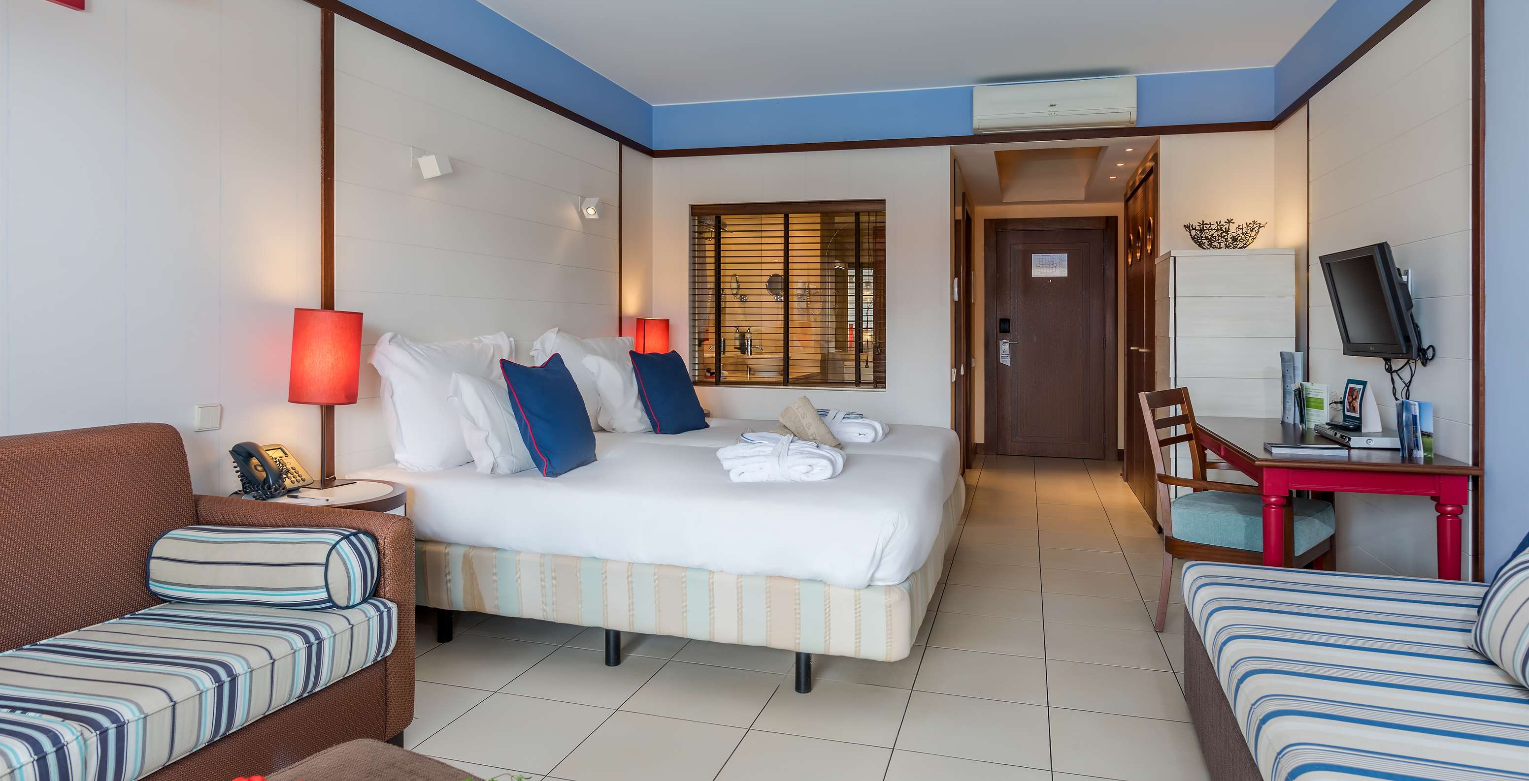 O Duplo Familiar do Pestana Porto Santo All Inclusive tem duas camas, dois sofás, uma secretária e uma televisão