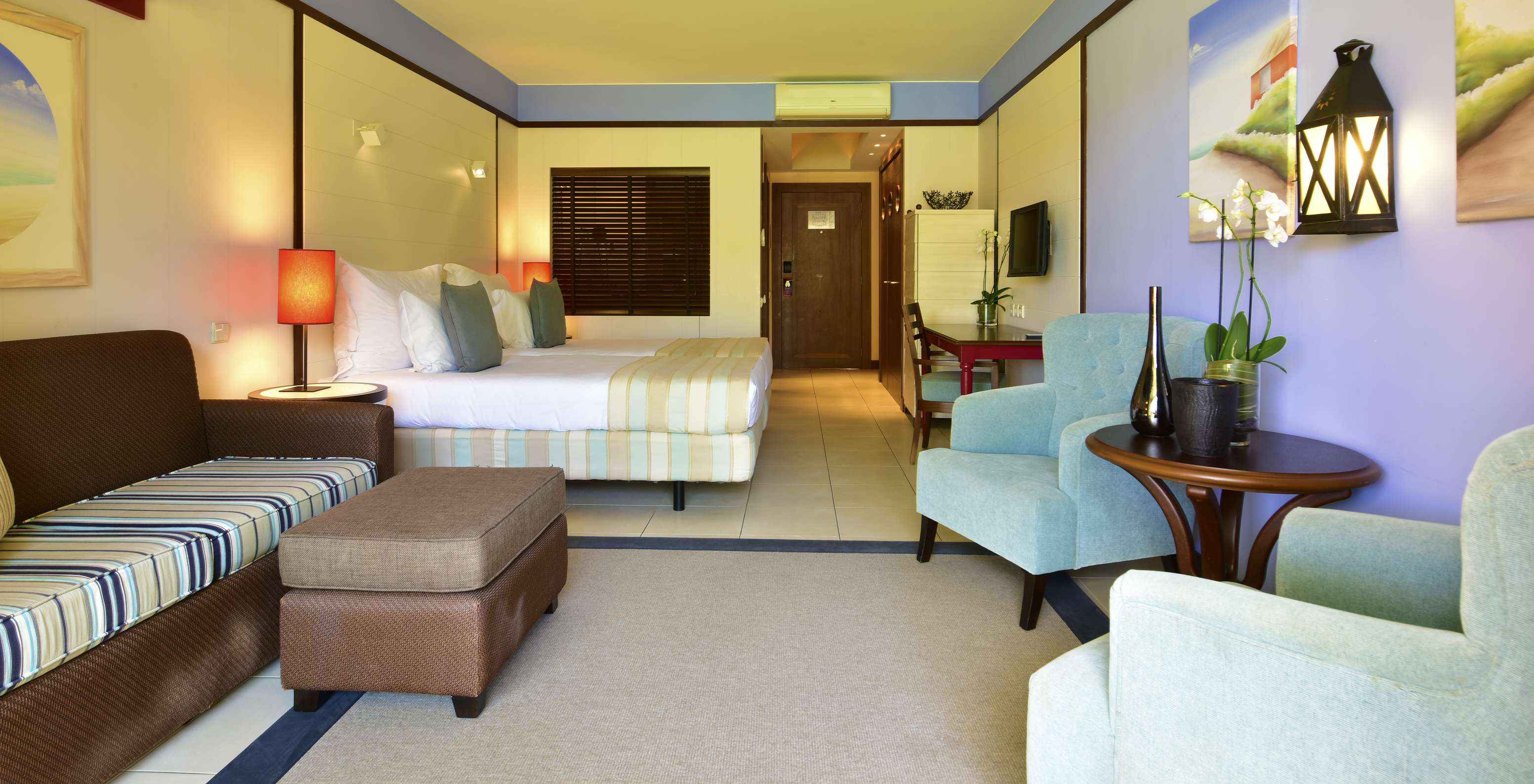 O Duplo Vista Piscina do Pestana Porto Santo All Inclusive tem um sofá, duas poltronas, duas camas, televisão e secretária