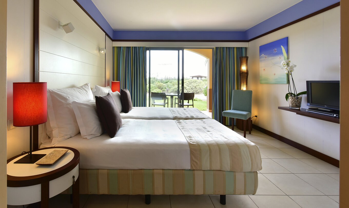 O Duplo Clássico do Pestana Porto Santo All Inclusive tem duas camas, uma cadeira e uma varanda com uma mesa e vista jardim