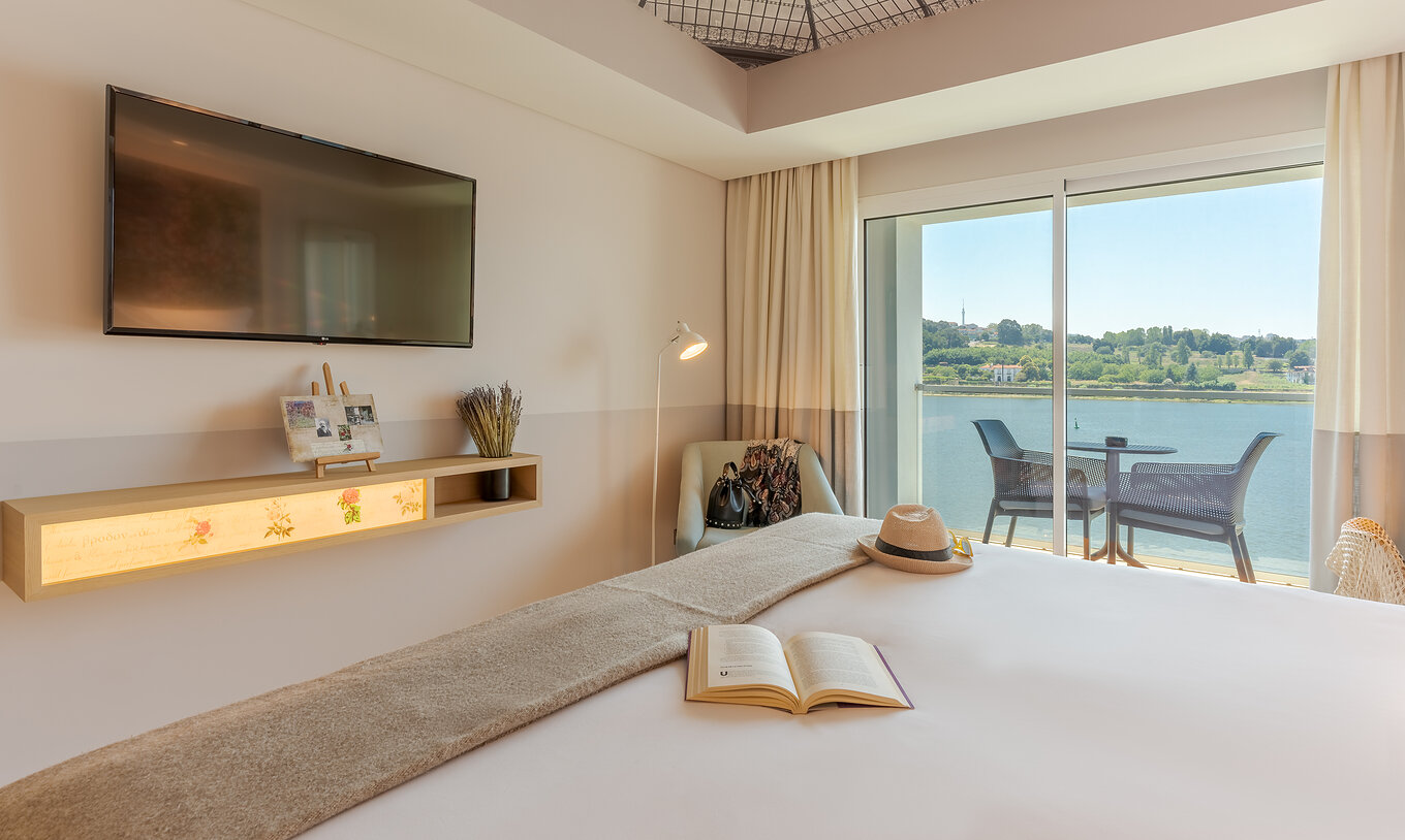 O quarto Deluxe River View do Pestana Douro Riverside conta com uma cama de casal, televisão e um cadeirão