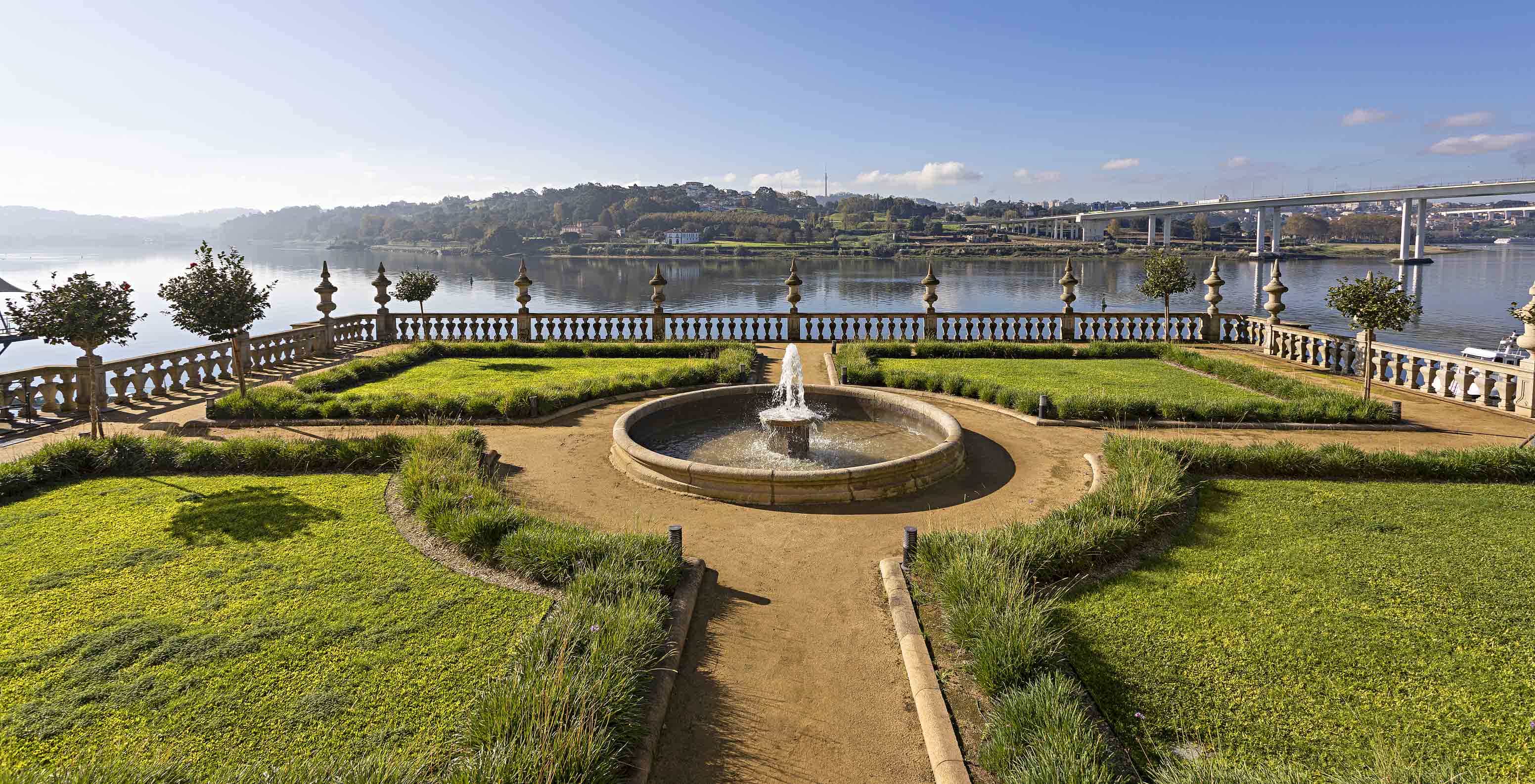 Vista dos jardins do Pestana Palácio do Freixo, com uma fonte no centro e o rio Douro atrás