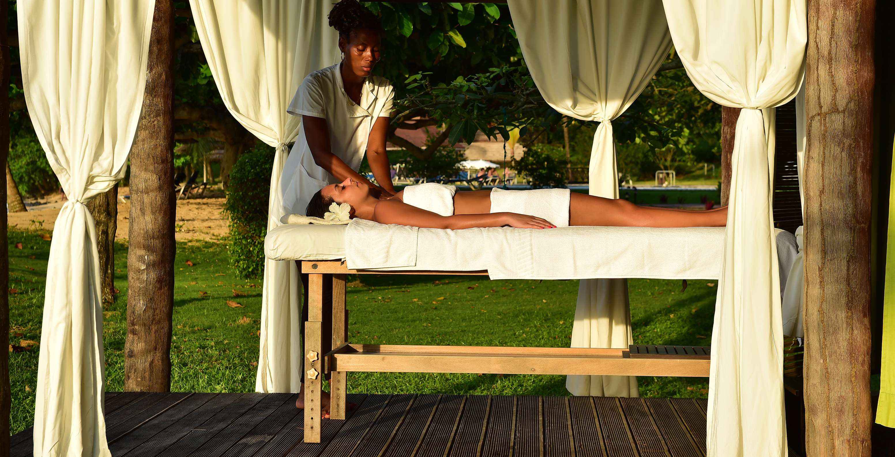 Rapariga com flor no cabelo recebe massagem ao ar livre no Hotel para Férias, com Piscina e Spa, em Frente à Praia