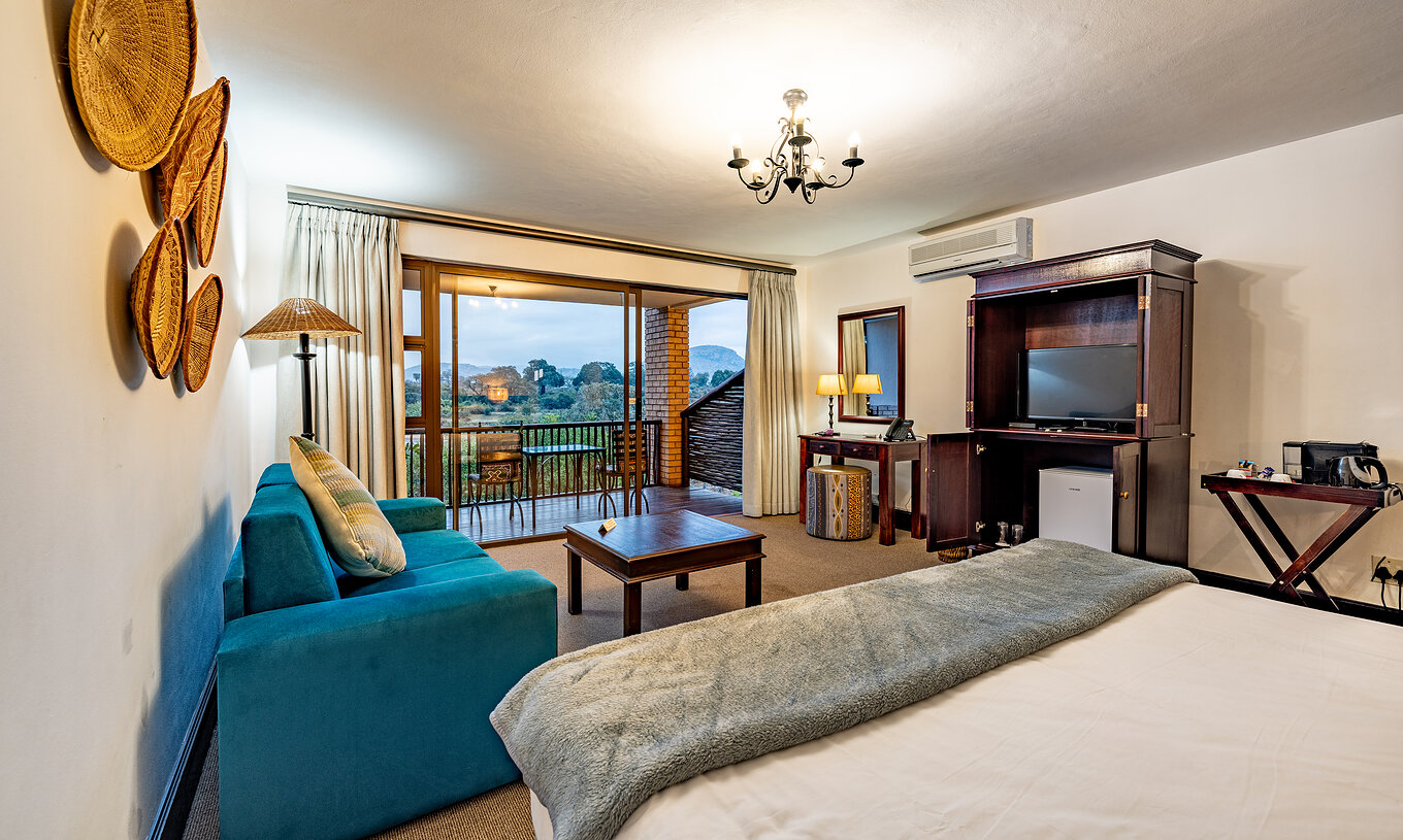 O Premium Room do Pestana Kruger Lodge tem uma zona de estar com sofá, televisão e decoração típica africana