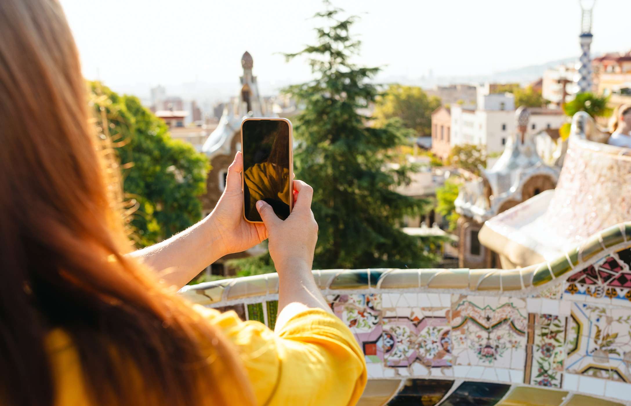 Pessoa a fotografar com o seu telemóvel a vista da cidade de Barcelona no famoso Parque Güell