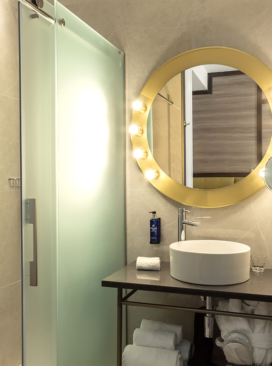 O Deluxe Grand com Vista do Pestana CR7 Gran Vía Madrid tem uma casa de banho com um espelho, lavatório e portas de vidro