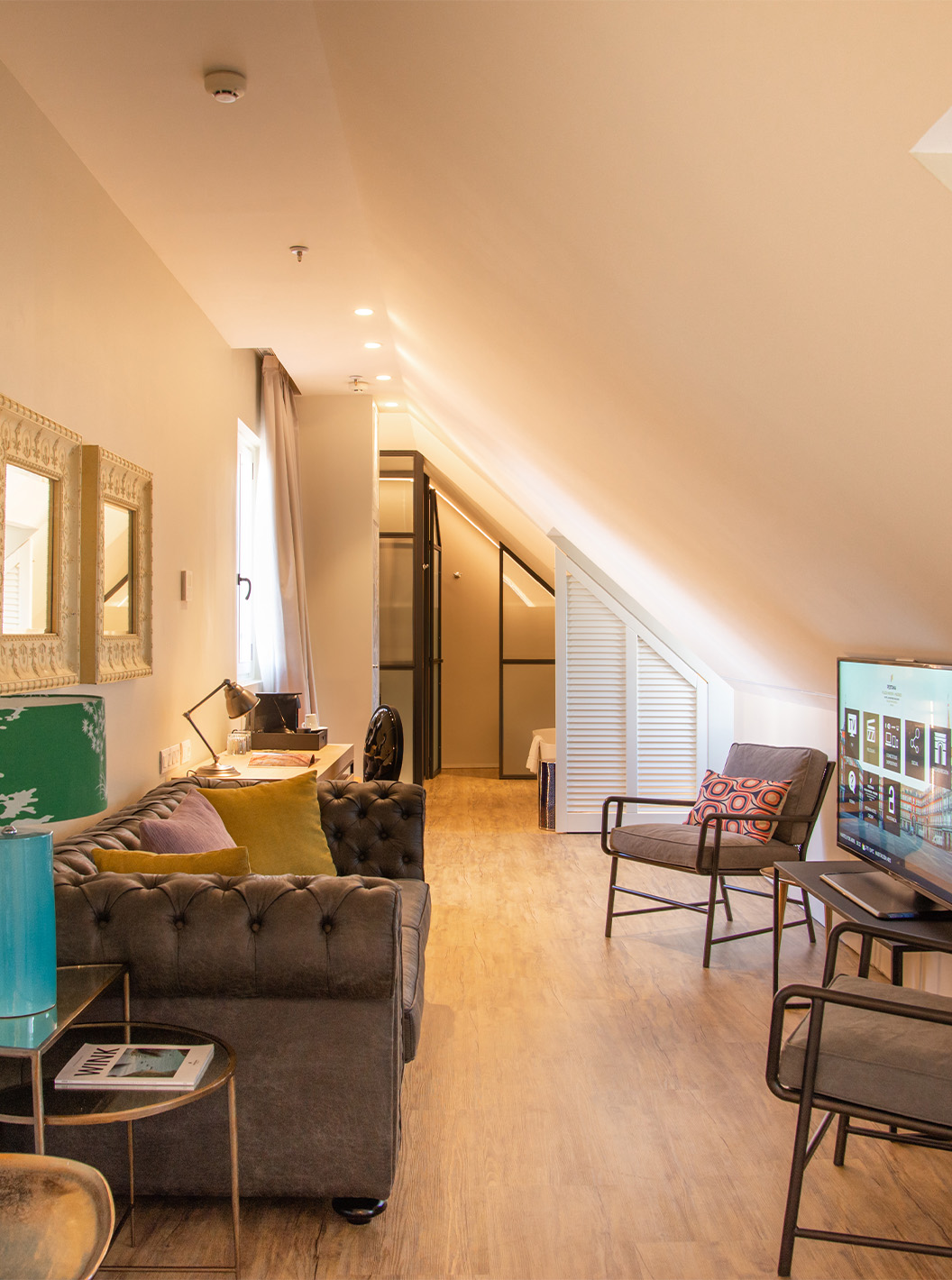 A Suite Plaza Mayor do Pestana Plaza Mayor Madrid tem uma sala de estar com sofá, cadeiras, televisão e quadros na parede