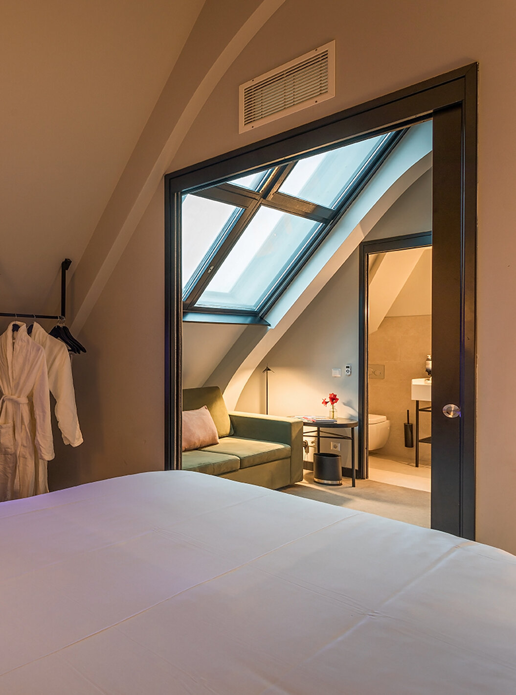 O quarto Loft  do Pestana Amsterdam Riverside tem um sofá verde, com uma mesa de centro, e dois roupões