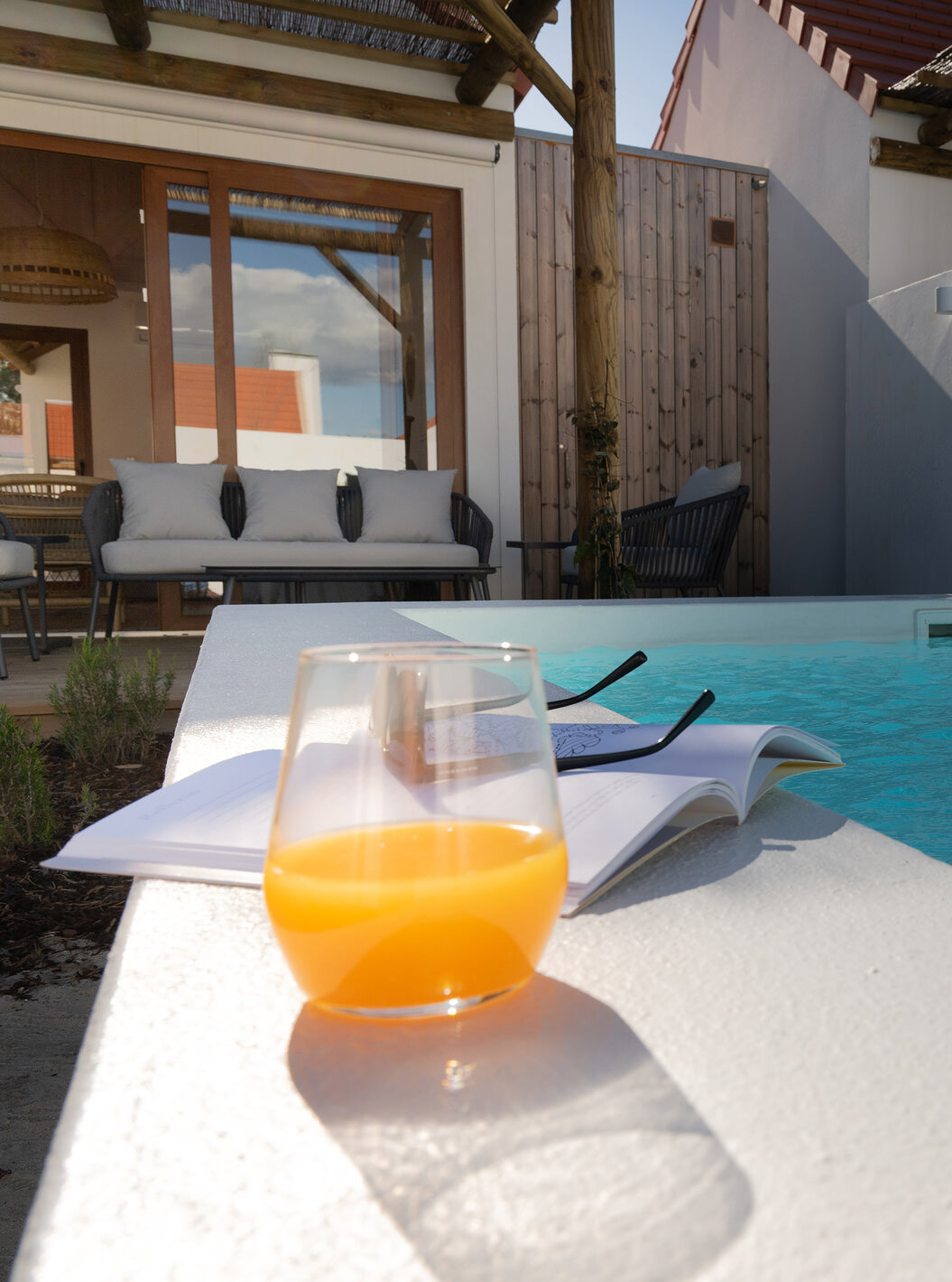 A Superior Green Villa do Pestana Comporta Village Residences tem um pátio com um copo de sumo e um livro perto da piscina