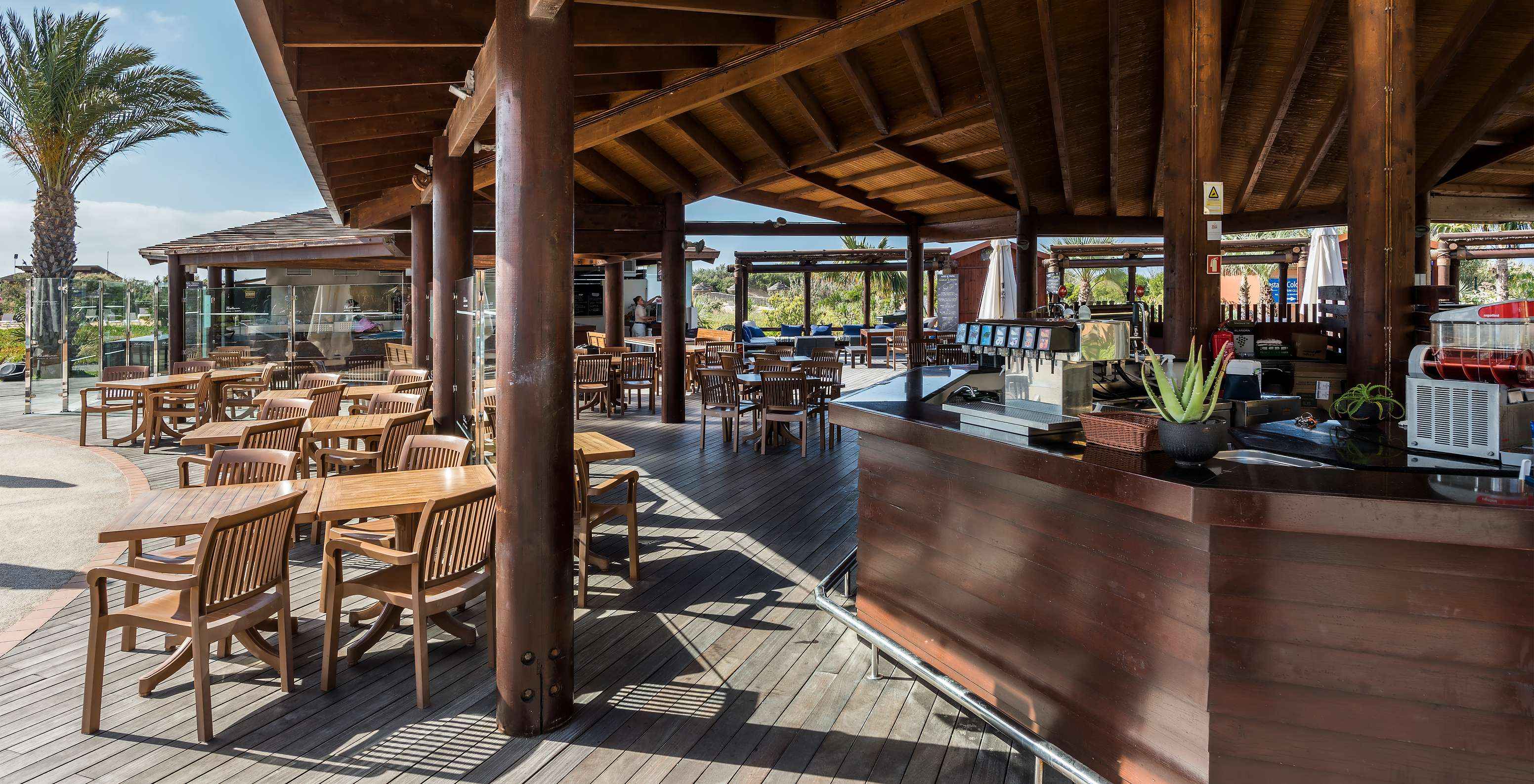 Restaurante do Pestana Porto Santo, Resort de 5 Estrelas no Porto Santo, com mesas de madeira e bar ao ar livre