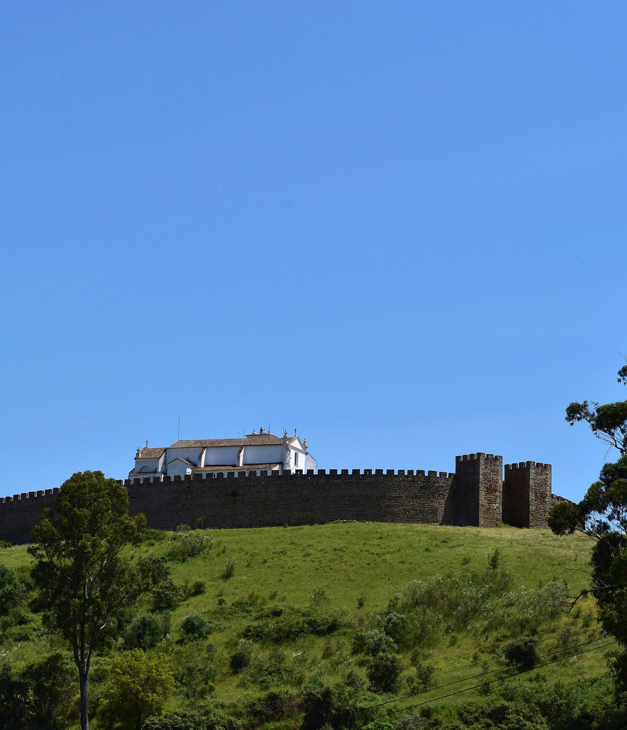 Historisch kasteel op een heuvel in Arraiolos, Alentejo, omgeven door groene landschappen en een heldere blauwe lucht