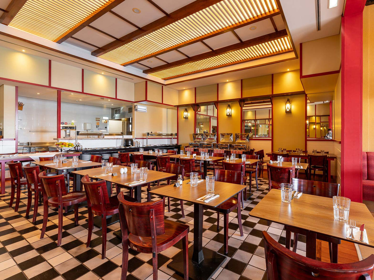 Restaurant Luigi van het 5-sterrenresort op Porto Santo heeft donkere tafels en stoelen met rode accenten.