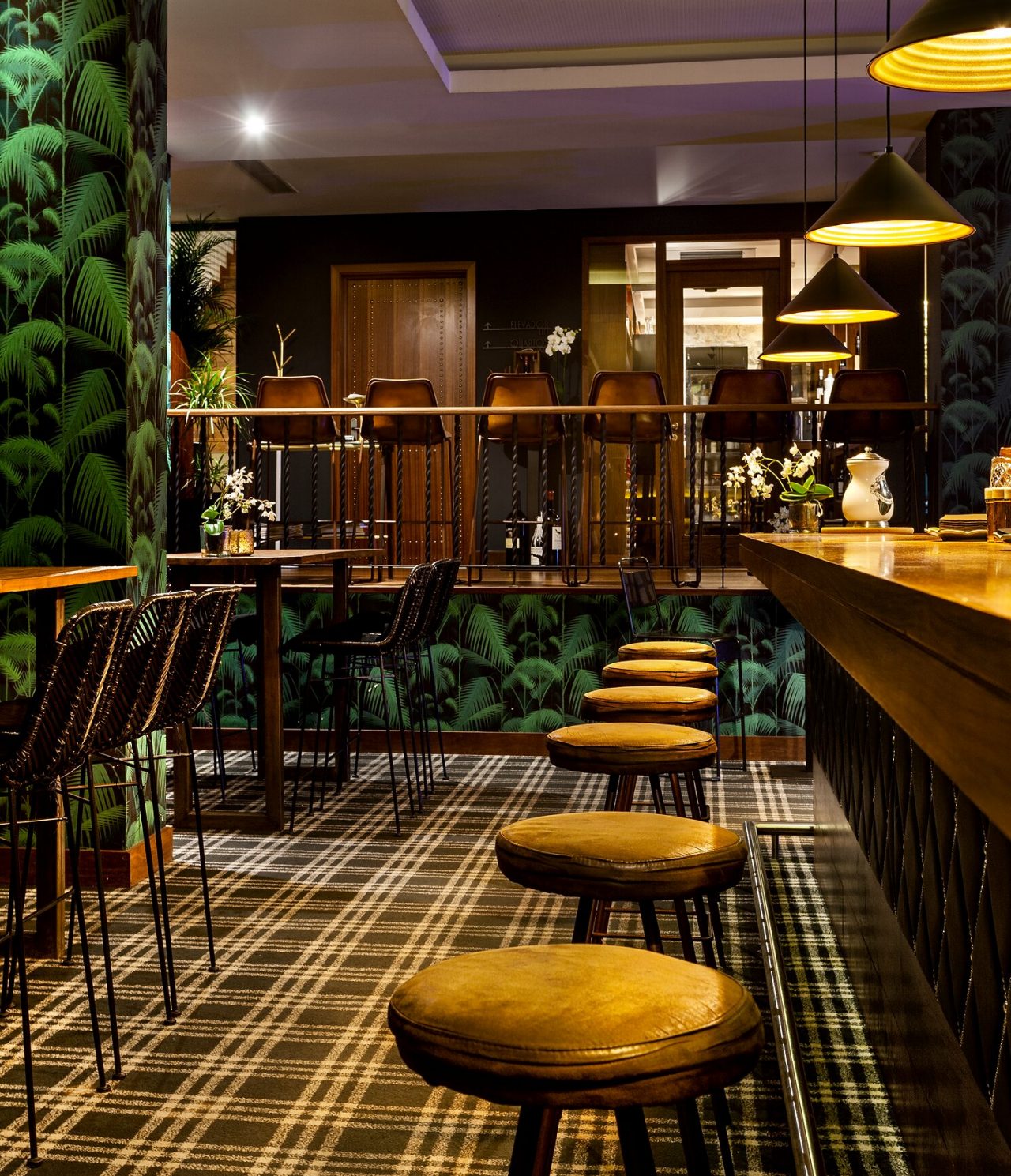 De Rib Bar, van het 5-sterrenhotel in het centrum van Porto, heeft een balie met hoge stoelen en tropisch behang