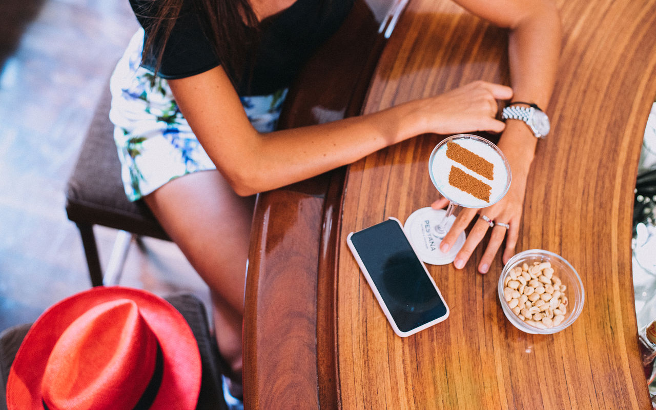 Meisje zit aan de hotelbar en drinkt een cocktail met een kaneellogo van Pestana Hotel Group