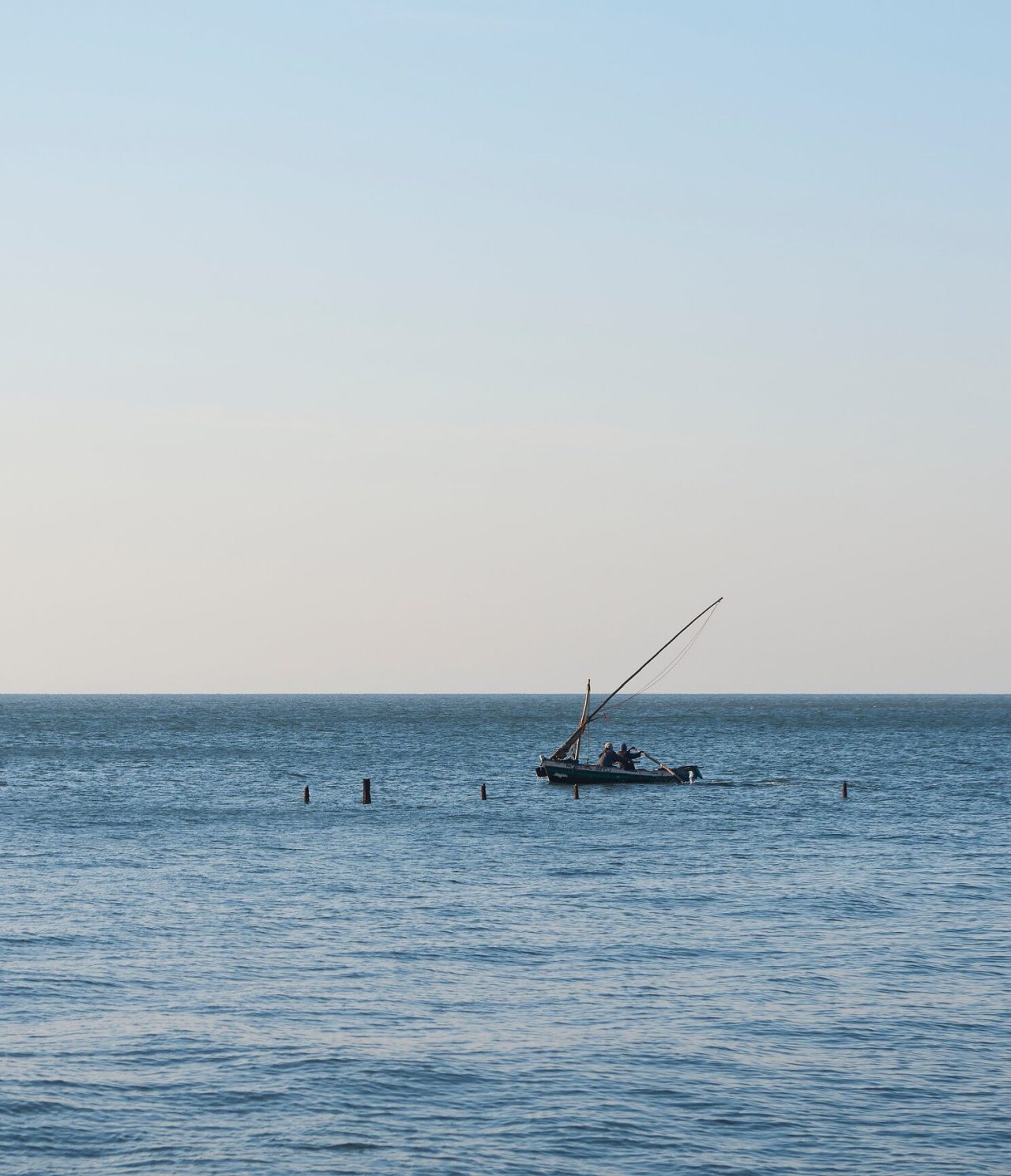  Open sea where a small boat with two men is stopped to fish