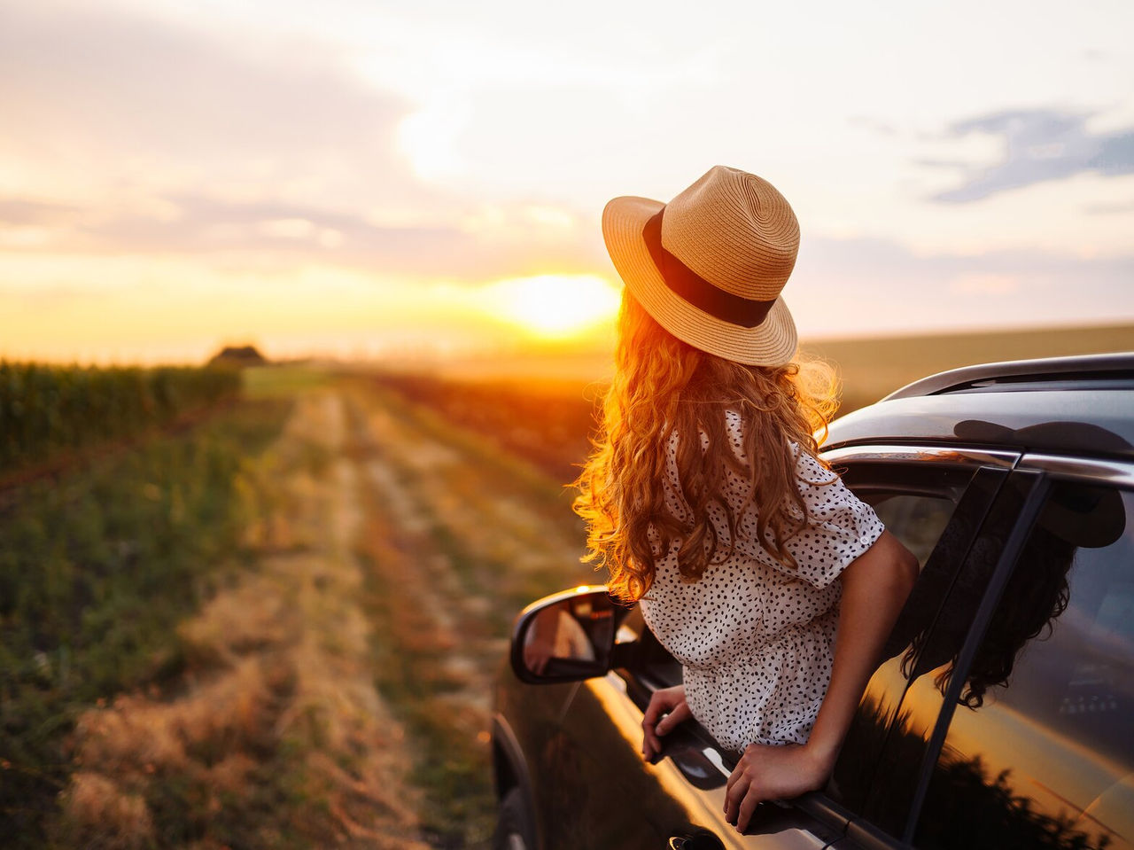 Person peeking out the car window while traveling through Alentejo at sunset, with stunning landscapes