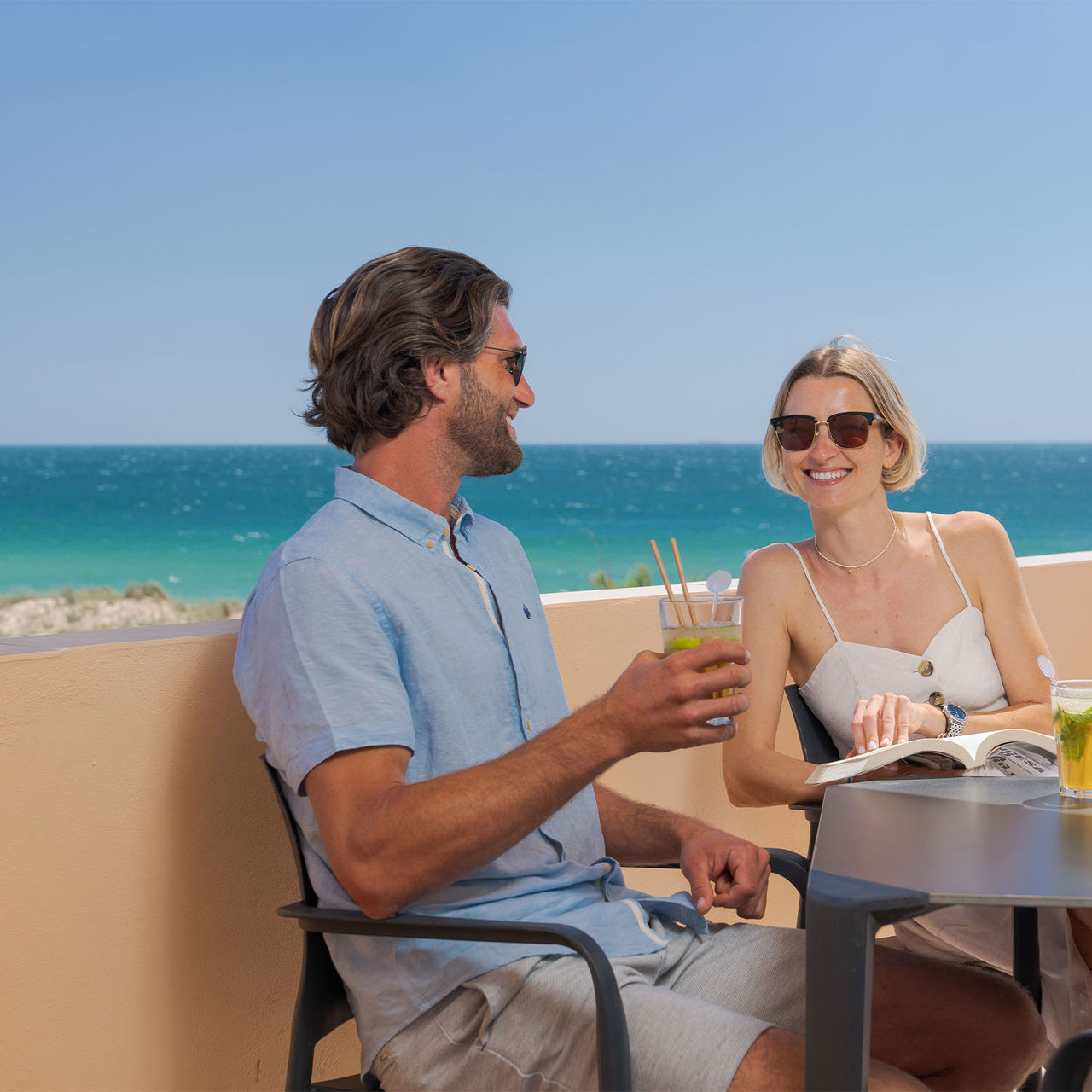 Couple drinks juice on the balcony of a private villa at Pestana Alvor Beach Villas, with a sea view