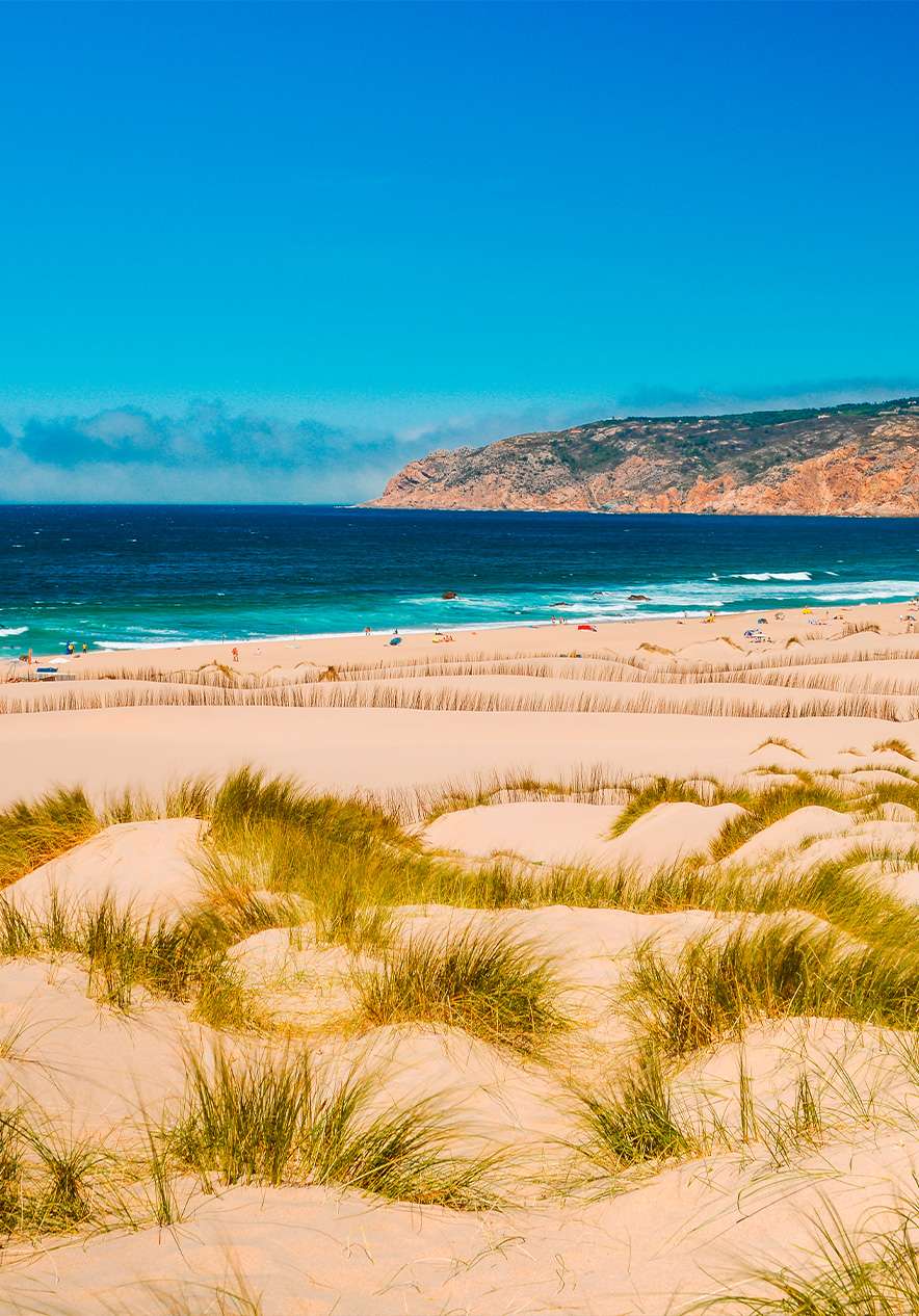 Guincho beach in Cascais where you see a perfect beach day with an expanse of golden sand dunes and blue sea