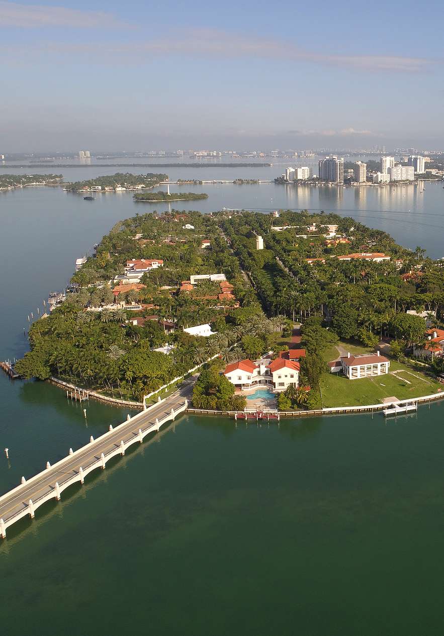Aerial view of Star Island in Miami with luxurious houses and vegetation with a bridge connecting the island to the city