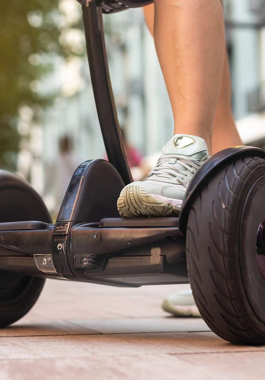 Person with feet on the base of a segway on a paved path