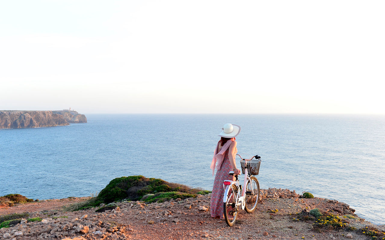Woman cycling on a dirt road through the dunes, with a bicycle from Pousadas de Portugal